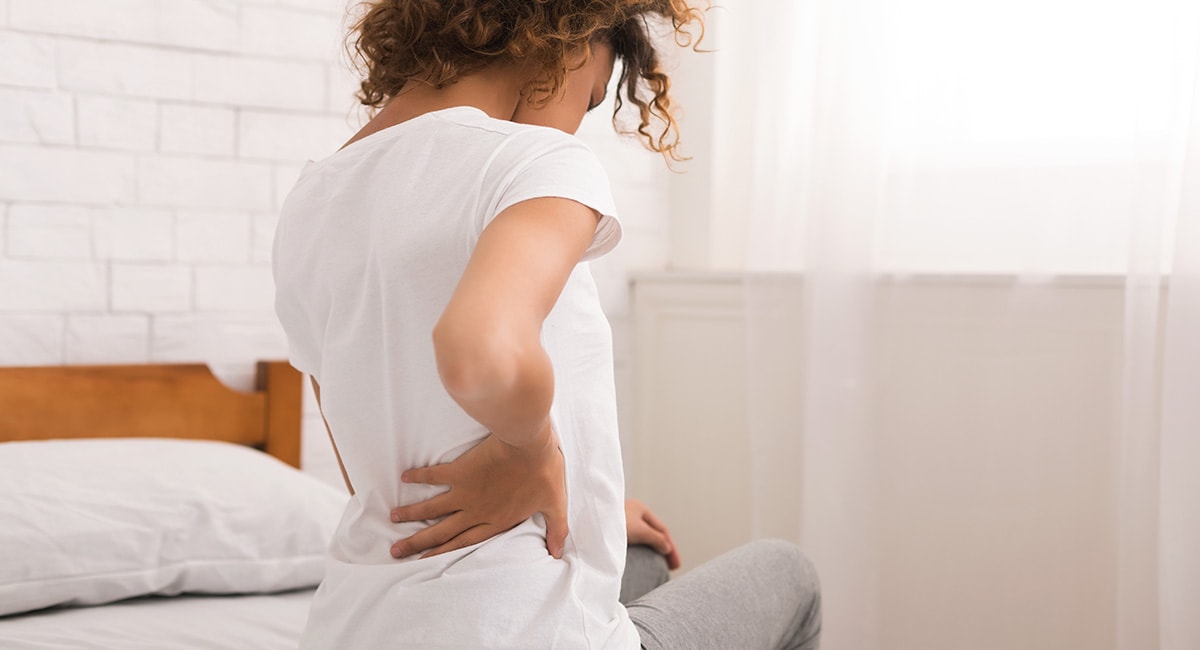 African American woman nursing her back. CBD cream for back pain. CBD salves for arthritis.