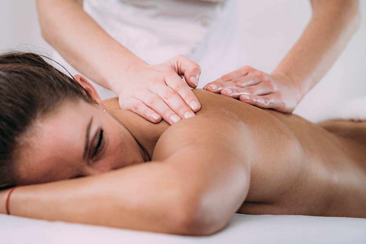 Adult woman with back pain getting a massage. Can cbd oil help manage pain? Buy hemp oil online USA.