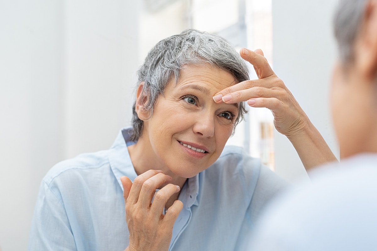 Mature woman looking at her wrinkles. Buy cbd for wrinkles online USA. CBD topicals for skincare.